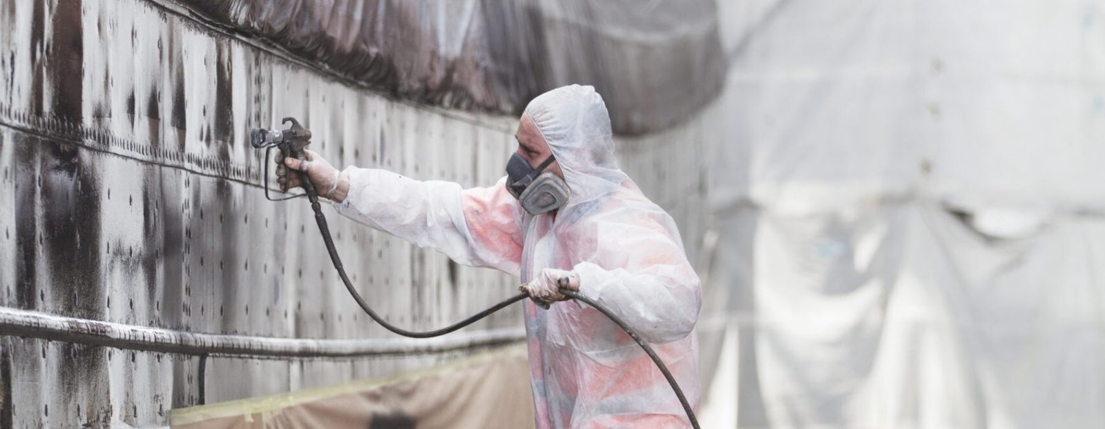 Worker spray-painting boat in shipyard